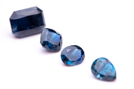 Four blue gemstones are lined up on a white background. The stones are all different shapes and sizes, but they all have a blue hue. Concept of elegance and sophisticationの写真素材