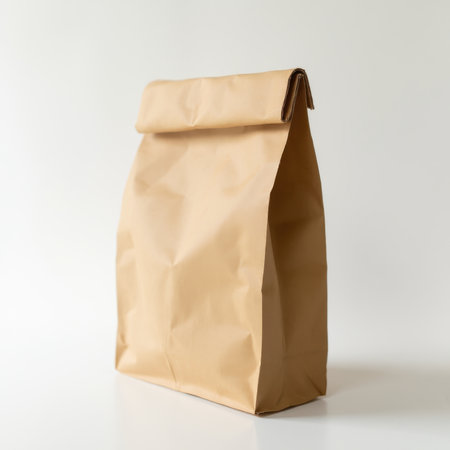 A brown paper bag is sitting on a white background. The bag is open and has a folded top. Concept of simplicity and minimalism, as the bag is made of a basic material and has a simple designの写真素材