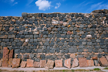 A wall made of stone blocks with a blue sky in the background. The wall is very tall and has a lot of space between the blocksの写真素材