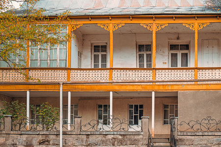 The old building has a yellow facade and a balcony. The balcony has a lot of ironwork and is covered in vinesの写真素材