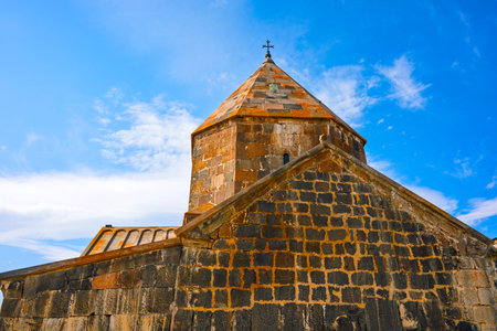 Sevan Monastery Sevanavank with a steeple and a cross on top. The building is old and has a lot of...