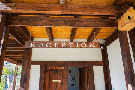 A wooden sign hanging from the ceiling that says "reception.". The sign is hanging from the ceiling and is made of woodの写真素材