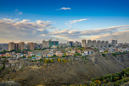 A city with a lot of buildings and a hill in the background. The sky is blue and there are some cloudsの写真素材