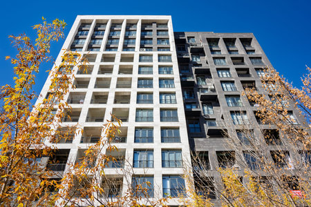 A tall building with a lot of windows and a sign on the side. The building is surrounded by trees...