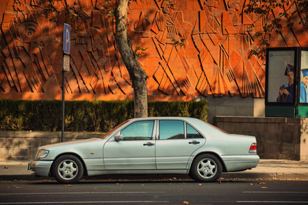 Yerevan Armenia 11.20.2025. A silver Mercedes car is parked on the side of the road in front of a building. The car is parked next to a tree and a poleのeditorial素材