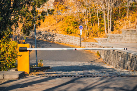 A yellow and white traffic gate is on a road. The gate is emptyのeditorial素材