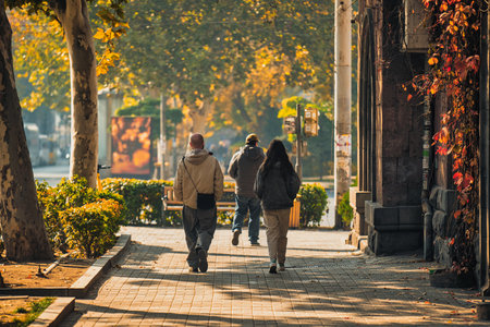 Yerevan Armenia 11.20.2025. A group of people walking down a sidewalk in a city. Scene is peaceful and relaxedのeditorial素材