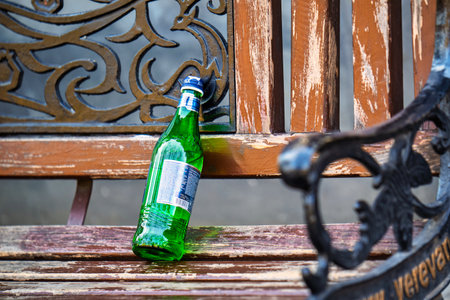Yerevan Armenia 11.20.2025. A bottle of Jermuk mineral water is sitting on a bench. The bench is wooden and has a metal frame. The bottle is upside down and he is empty. The scene gives off a casual and relaxed vibeのeditorial素材