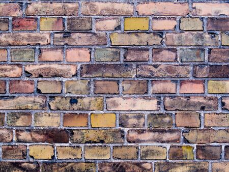 Multi-color old and grunge brick wall. Vintage background. Ancient wall structure closeupの写真素材