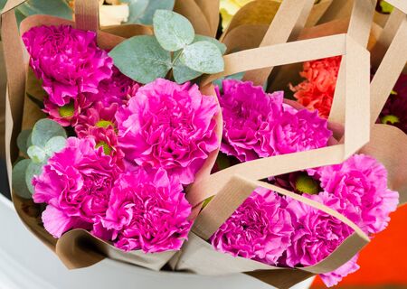Bunches of flowers wrapped in craft paper packages for sale. Fresh purple carnation flowers. Colorful florist display. Top down view. Floral bouquet. Bright colors for celebration, romantic gift.の写真素材