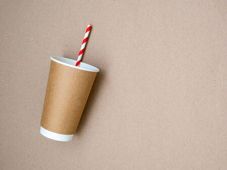 The concept of a world without plastic and a clean planet. Takeaway coffee mug with paper white and red drinking straw on craft paper background. Space for text. Zero waste. Flat lay, top viewの写真素材