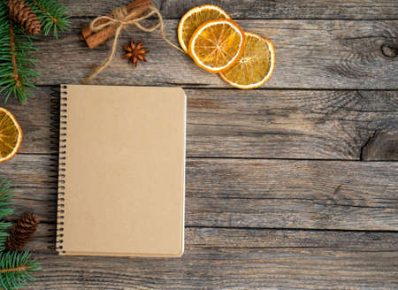 Christmas mockup. To do list. Blank sheet of craft paper with fir branches, orange chips, cinnamon, cones and anise on vintage wooden table. New year resolutions concept. Flat lay, copy space.の写真素材