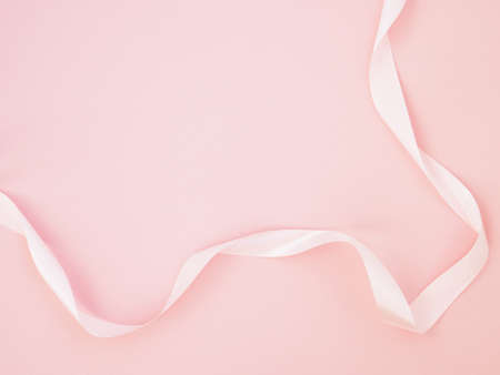 Pink satin ribbon on a pastel pink background top view Flat Lay with copy space. Element of holiday decoration, greeting card, birthday present, Valentines Day, March 8.の写真素材