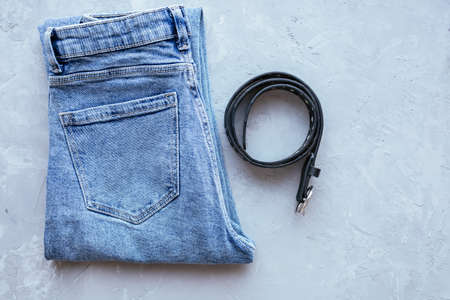 Classic blue woman jeans with belt on grey concrete background. Denim fabric. Casual wear. Top view. Comfortable style cloth. Flat layの写真素材