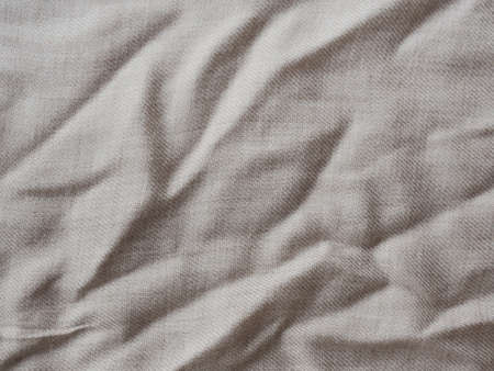 Minimalistic background for design. Wrinkle beige linen texture. Detailed closeup. Rustic crumpled vintage cotton fabric. Comfortable style cloth. Wavy folds natural material.の写真素材