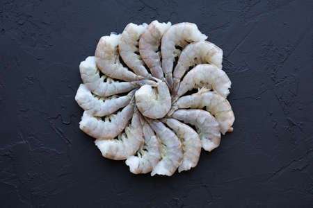 Fresh Vannamei shrimps without head for meal preparation. Raw uncooked Asian tiger prawns. Pacific white shrimp or king prawn in black background. Natural seafood with low fat and high protein.の写真素材
