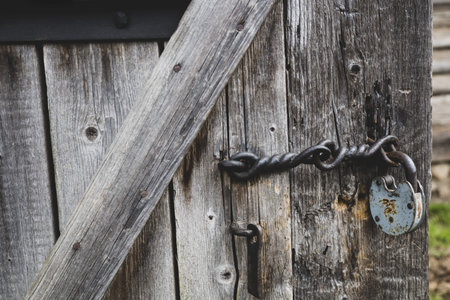 Vintage rusty padlock on old wooden door of abandoned house. Retro locks closeup. Village...