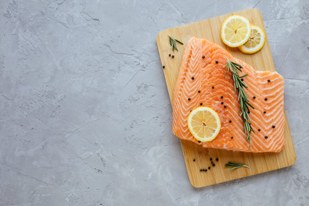 Raw salmon fillet with lemon, rosemary and pepper on cutting board. Fresh organic wild Atlantic fish...