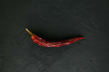 Most popular spicy herb for Thai food. Dried fruit of Capsicum frutescens. Whole dry red chili hot pepper on black stone background. Spices and seasonings for cooking. Top view. Soft focusの写真素材