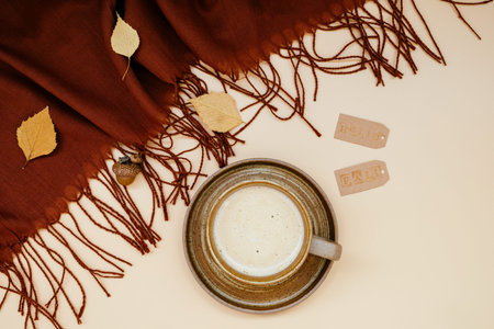 Atmospheric autumn composition. Fall background with mug of coffee, deep brown cashmere scarf and...