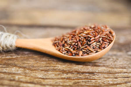 Raw red unpolished rice in spoon. Rubin grains closeup. Bhutanese. Uncooked organic brown rice for traditional Asian cuisine. Popular agriculture cereal. Healthy eating and dietary. Soft focusの写真素材