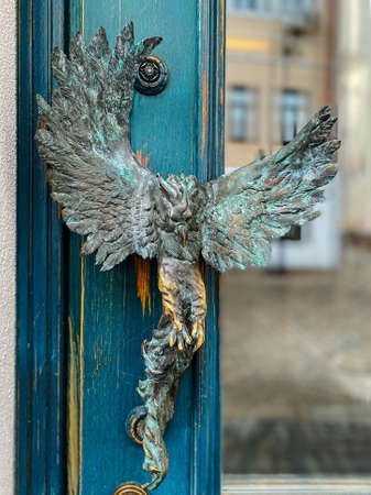 Turquoise wooden and glass entrance with antique door handle in the form of a bird. Unusual details of ornate door. Vintage iron door knob.の写真素材