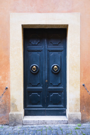Elegant old blue double door entrance of building in Europe. Vintage wooden doorway of ancient stone house. Simple bright colored wood door with ring door handle. Architecture in Italy.の写真素材