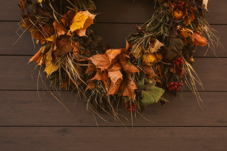 Autumn or Fall composition. Fall leaves, berries, grass and fruits. Mood, lifestile, still life concept. Thanksgiving decorations. Beautiful autumnal wreath hanging on wooden background. Copy space.の写真素材