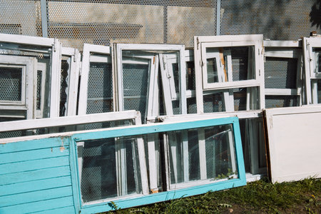 Construction waste for disposal. Heap of old wooden window frames with glass outdoors. Energy saving technology upgrade. Renovation and reconstruction concept. Replacement of windows in building.の写真素材