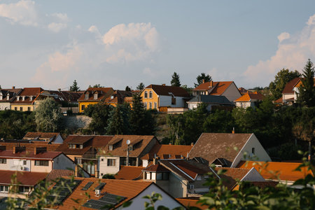 Orange, brown and red tiled roof of the houses with solar panels. Traditional street houses of Eger with yellow and white walls. Different size and colors building in Europe. Architecture in Hungaryの写真素材