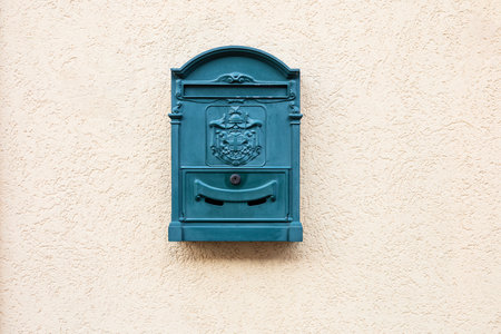 Traditional old turquoise post box on pastel plaster texture wall in Hungry. Metal green blue mailbox. Copy space. Symbol of communication and connectionの写真素材