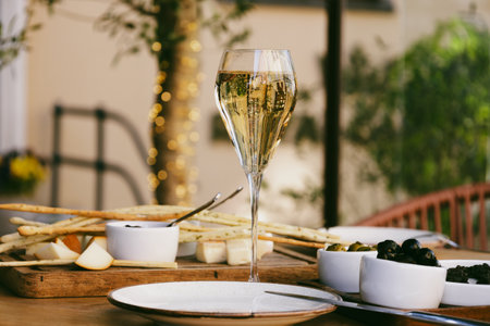 Elegant tall flute of chilled sparkling champagne with different snacks on an elegant formal dining table at outdoor cafe or restaurant in pedestrian street in Europe. Luxury served table at terrace.の写真素材