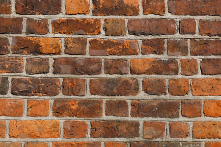 Wall of old red clay bricks. Ruined vintage stone background. Rough aged masonry backdrop. Surface of grunge brick texture for design and decoration. Loft style for exterior and interior decorationの写真素材