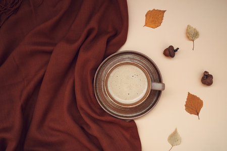 Atmospheric autumn composition. Fall background with mug of coffee, deep brown cashmere scarf and leaves on pastel colors. Sunday relaxing, memories and still life concept. Flat layの写真素材
