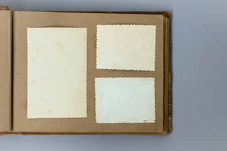 Clear blank photo frames to placed your pictures or text on old family album on grey background in retro style. Family traditions, memories and nostalgia concept. Antique album with old photos.の写真素材