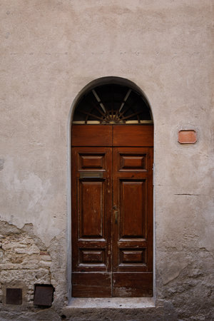 Elegant old double door entrance of brick pink building in Europe. Vintage wooden doorway of ancient stone house. Simple brown wood door. Architecture in Italy.の写真素材