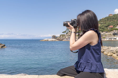 Young photographer takes a photo towards the sea