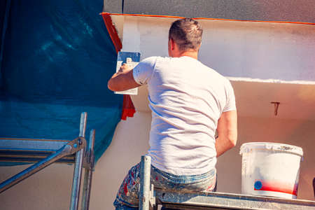 Construction workers plaster the facade of the house. Application Of Facade Plaster. Elevation of the building. Four workers are plastering the facade of the building.の写真素材