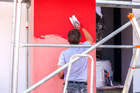 Construction workers plaster the facade of the house. Application Of Facade Plaster. Elevation of the building. Four workers are plastering the facade of the building.の写真素材