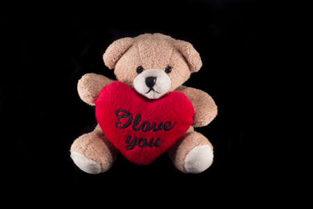 Teddy bear with red heart isolated on black backgroundの写真素材