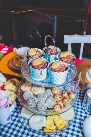 Colorful Tea party with chocolate cupcakes, biscuits, muffins, sweet balls, sausage rolls, pumpkin...