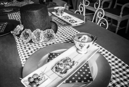 Butternut and pumpkin soup, tomato and caramelized onion pastry tart with lettuce salad served on a white rectangular plate and gold circular plate underneathの写真素材