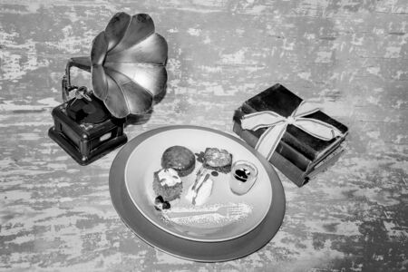 Chocolate brownie, malva pudding, pumpkin spice cake with glazed frosting and lemon curd in a small glass on a colorful plate with icing sugar decoration, old grammar phone and antique booksの写真素材