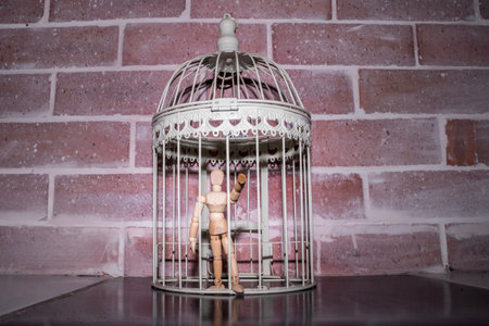 Wooden Human Manikin locked inside a white ornamental bird cage