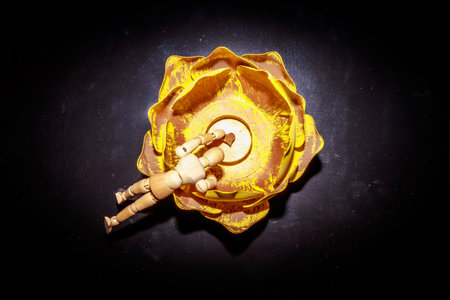 A Wooden Human Manikin posing in a yellow ornamental flower