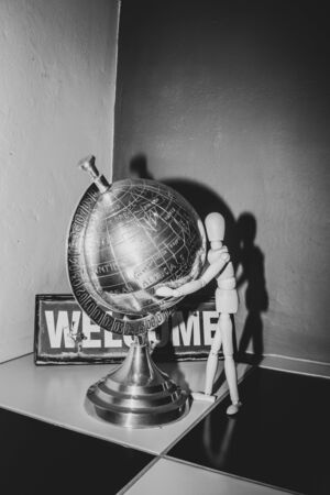 Wooden Human Manikin posing with an ornamental silver world globeの写真素材