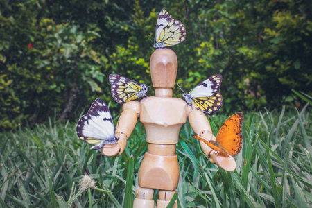 Wooden Human Manikin posing with an orange and yellow Butterflies sitting on the manikin, South...