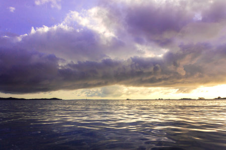 View of coastline on Nosy Komba Island lined with palm trees and boats floating in the sea at...
