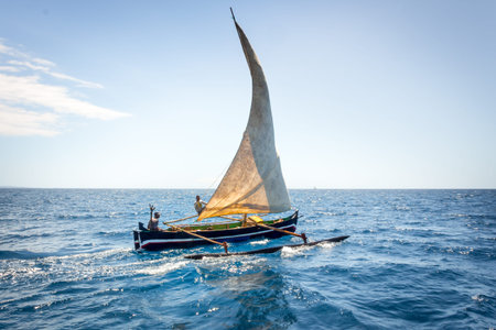 View of Nosy Komba Island coastline with a sail boat sailing on the sea, Nosy Komba, Madagascar