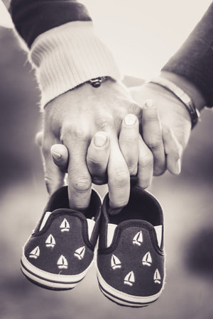 Maternity photo shoot, a father and mother holding the new babies shoes in their hands, Cape Town,...